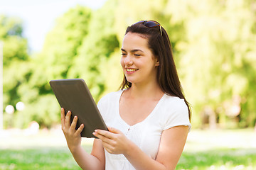 Image showing smiling young girl with tablet pc sitting on grass