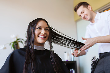 Image showing happy woman with stylist cutting hair at salon