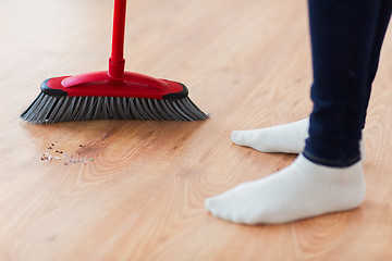 Image showing close up of woman legs with broom sweeping floor