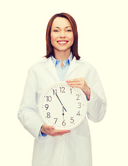 Image showing smiling female doctor with wall clock