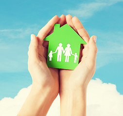 Image showing hands holding green house with family