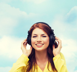 Image showing smiling young girl in headphones at home