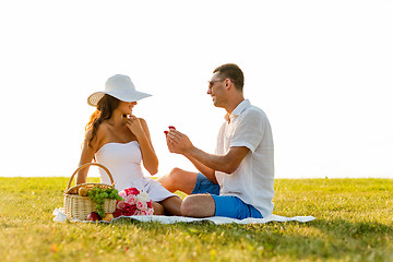 Image showing smiling couple with small red gift box on picnic