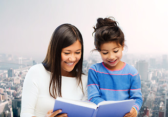 Image showing happy mother and little daughter reading book