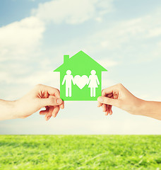 Image showing hands holding green house with family