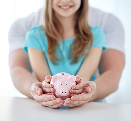 Image showing close up of family hands with piggy bank