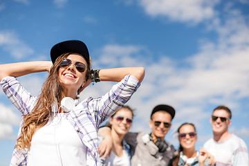 Image showing teenage girl with headphones and friends outside