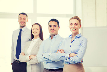 Image showing smiling businesswoman in office with team on back