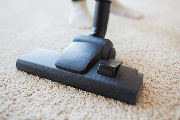 Image showing close up of vacuum cleaner cleaning carpet at home