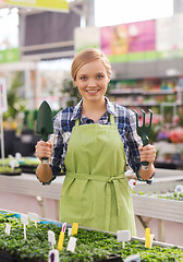 Image showing happy woman with gardening tools in greenhouse