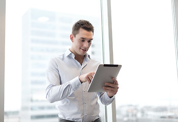 Image showing smiling businessman with tablet pc in office