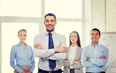 Image showing smiling businessman in office with team on back