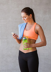 Image showing woman with smartphone and bottle of water in gym