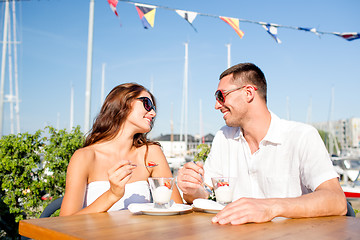 Image showing smiling couple eating dessert at cafe