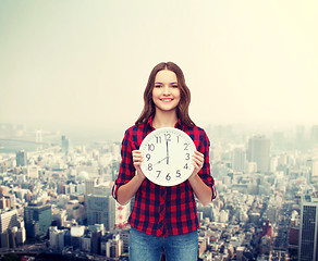 Image showing young woman in casual clothes with wall clock