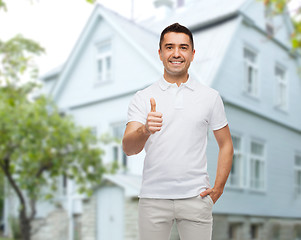 Image showing man showing thumbs up over house background