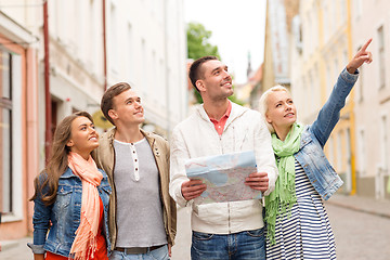 Image showing group of smiling friends with map exploring city