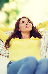 Image showing smiling young woman lying on sofa at home