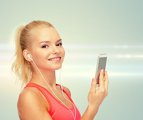 Image showing smiling sporty woman with smartphone and earphones