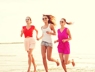 Image showing group of smiling women running on beach