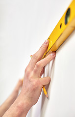 Image showing close up of male hands with level measuring wall