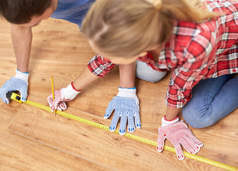 Image showing happy couple with ruler measuring parquet board