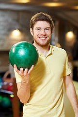 Image showing happy young man holding ball in bowling club