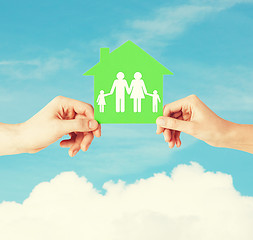 Image showing hands holding green house with family