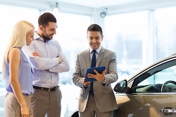 Image showing happy couple with car dealer in auto show or salon