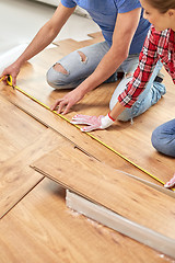 Image showing happy couple with ruler measuring parquet board