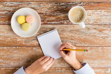 Image showing close up of hands, notebook, coffee and cookies