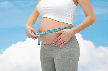 Image showing close up of pregnant woman measuring her tummy