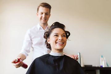 Image showing happy woman with stylist making hairdo at salon