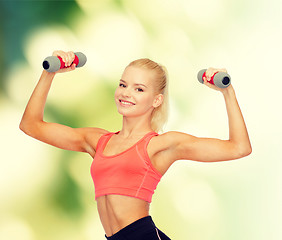 Image showing smiling beautiful sporty woman with dumbbells