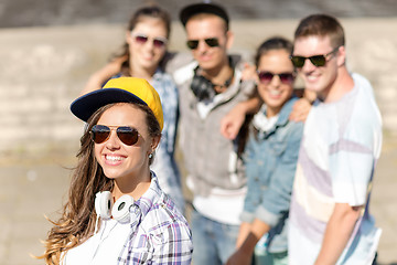 Image showing teenage girl with headphones and friends outside