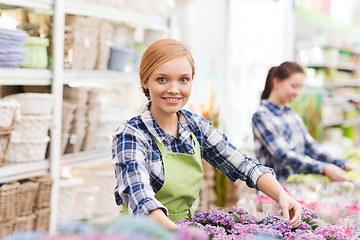 Image showing happy woman taking care of flowers in greenhouse