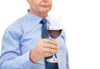 Image showing close up of senior man holding glass with red wine