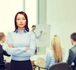 Image showing smiling businesswoman with crossed arms at office