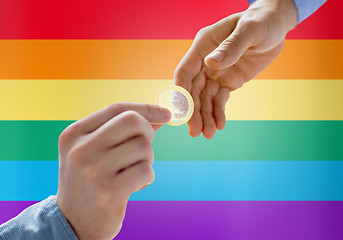 Image showing close up of male gay couple hands giving condom