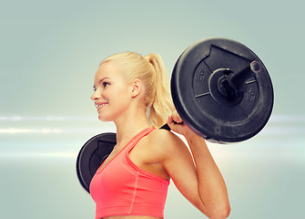 Image showing smiling sporty woman exercising with barbell