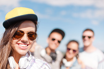 Image showing teenage girl with headphones and friends outside