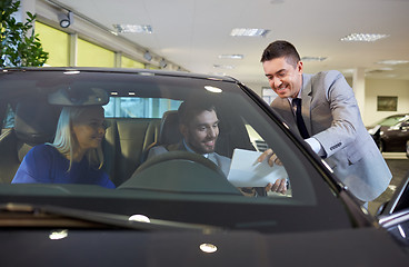 Image showing happy couple with car dealer in auto show or salon