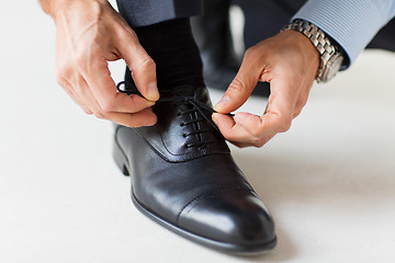 Image showing close up of man leg and hands tying shoe laces