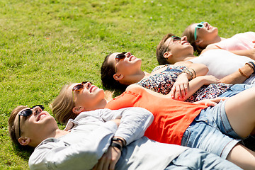 Image showing group of smiling friends lying on grass outdoors