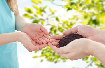 Image showing close up of father and girl hands holding sprout