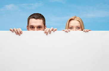 Image showing happy couple hiding behind big white blank board