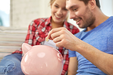 Image showing close up of couple with piggy bank sitting on sofa