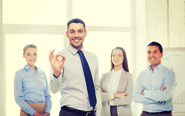 Image showing smiling businessman showing ok-sign in office