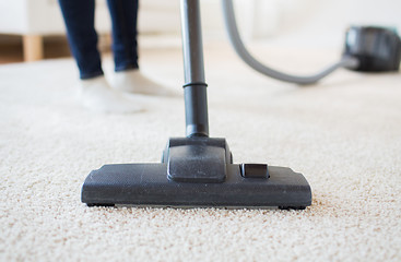 Image showing close up of woman legs with vacuum cleaner at home