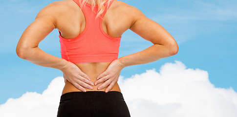 Image showing close up of sporty woman touching her back